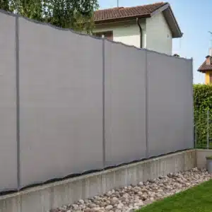 Telo ombreggiante grigio installato su recinzione da giardino con occhielli perimetrali