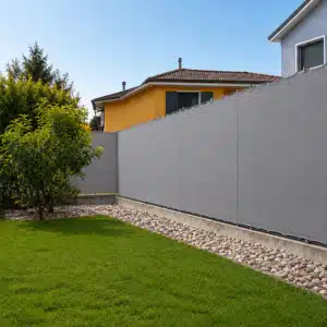Telo ombreggiante grigio su misura installato su recinzione con bordatura e occhielli
