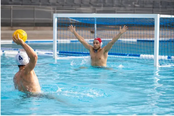 Giocatore tira verso una porta da pallanuoto con rete in piscina.