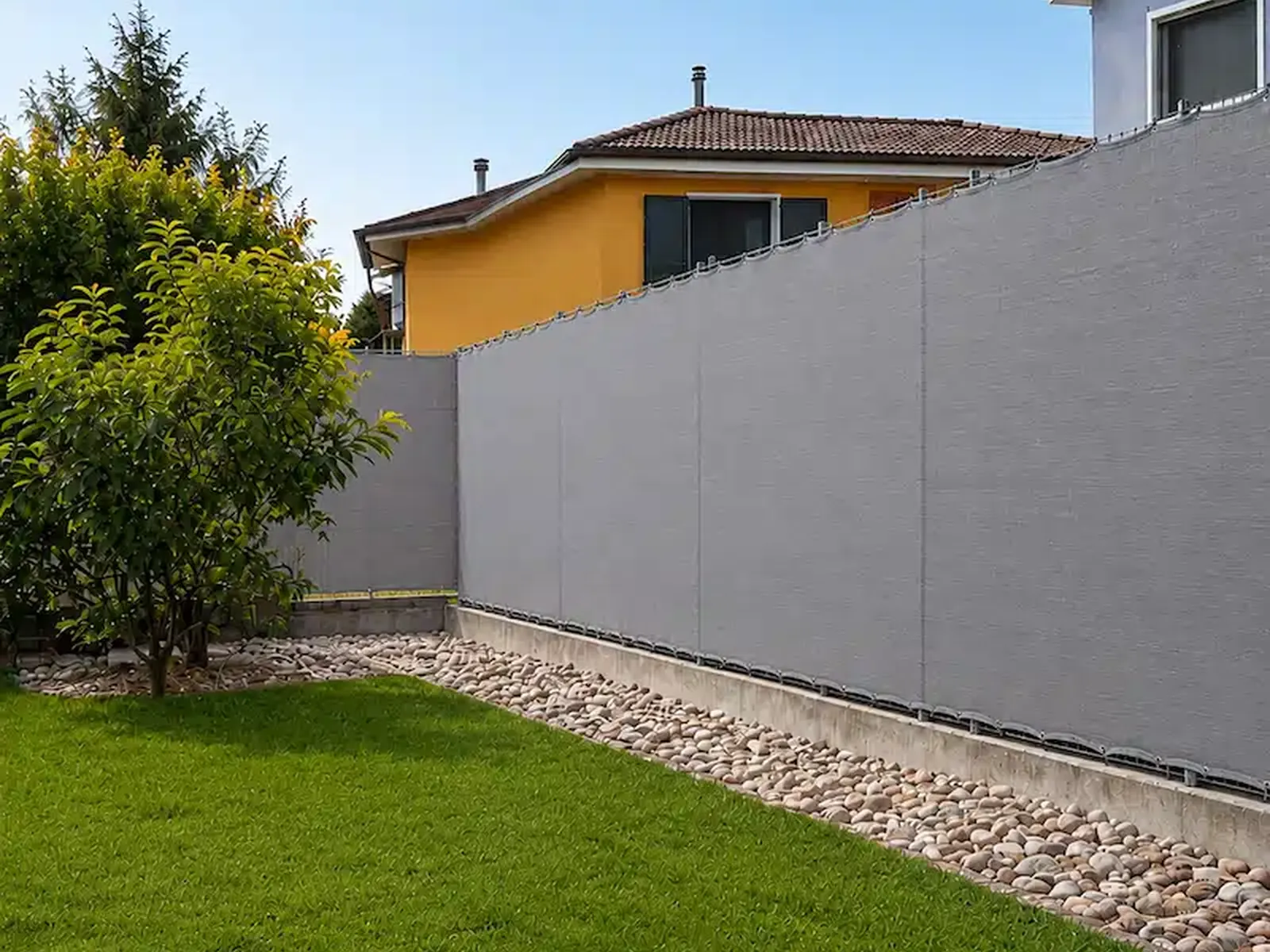Telo ombreggiante grigio su misura installato su recinzione con bordatura e occhielli